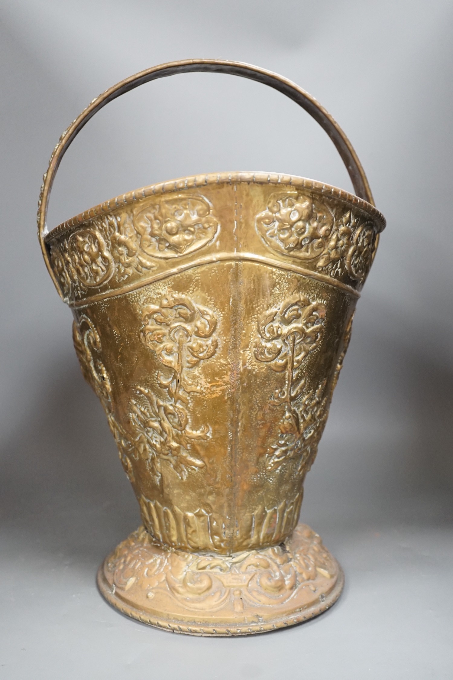 An embossed brass helmet coal bucket, 48cms high